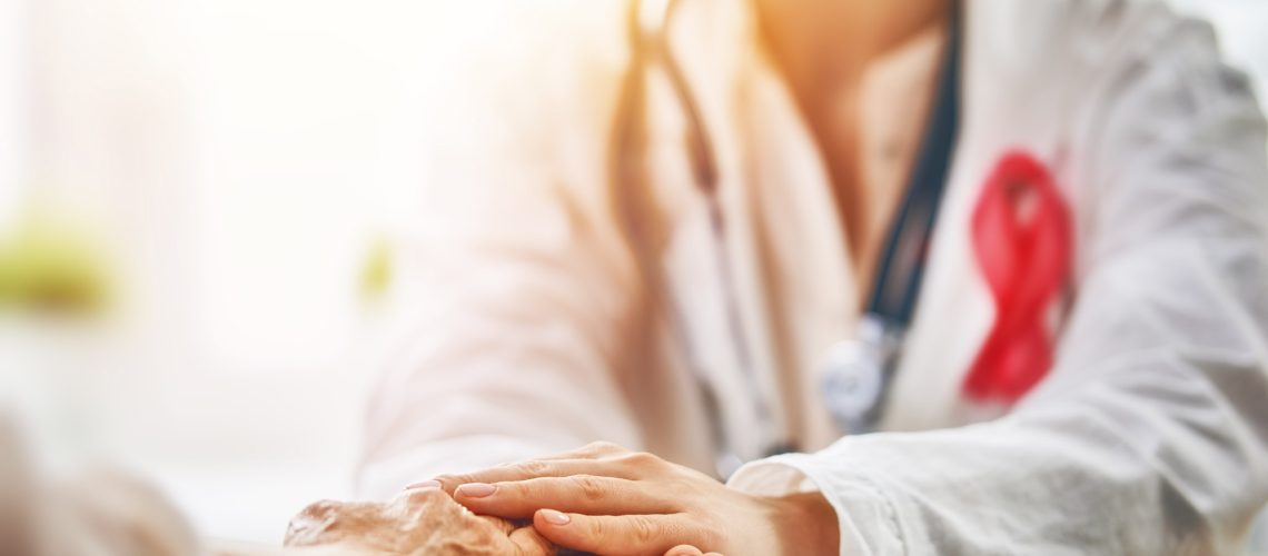Pink ribbon for breast cancer awareness. Female patient listening to doctor in medical office. Support people living with tumor illness.